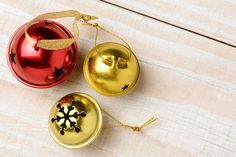 three christmas ornaments sitting on top of a wooden table next to each other, one red and one gold ornament