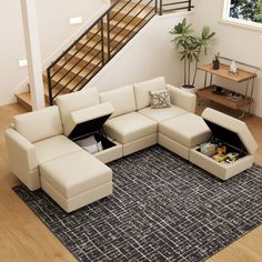 a living room with a sectional couch and coffee table on the floor next to a stair case