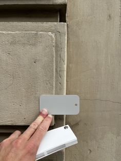 a hand is holding an electronic device in front of a door handle on the outside of a building