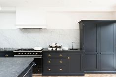 a kitchen with black cabinets and marble counter tops