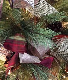 a close up of a christmas tree with ribbons and pine cones on it's branches