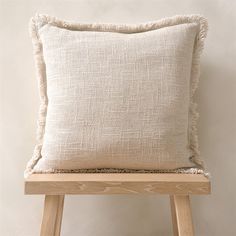 a white pillow sitting on top of a wooden stool