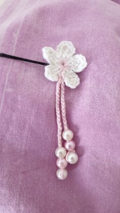 a close up of a pink pillow with pearls and a crochet flower on it