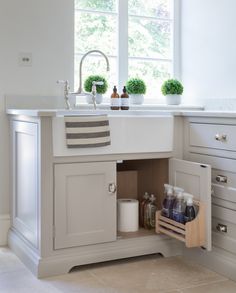 an open cabinet in the middle of a kitchen with white cabinets and drawers on both sides