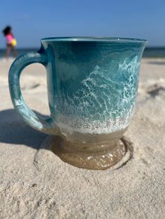 a blue mug sitting on top of a sandy beach