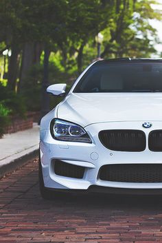 a white car parked on the side of a road next to a tree filled street