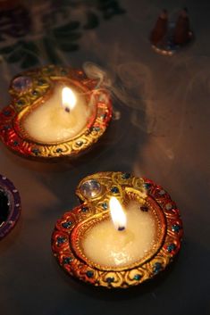 three lit candles sitting on top of a table next to an ornate plate with a candle in it