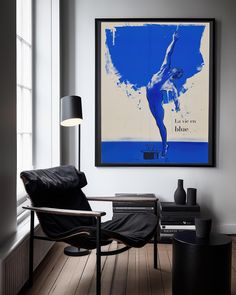 a living room with a chair and a poster on the wall above it that has a ballerina in blue