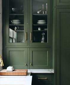 a kitchen with green cabinets and white counter tops