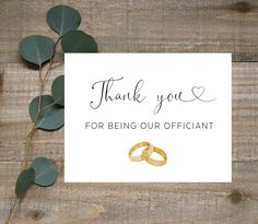 a thank card with two gold wedding rings on it and eucalyptus leaves next to it