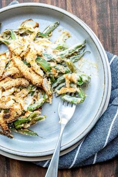 a white plate topped with green beans covered in gravy next to a fork