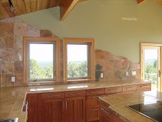 an empty kitchen with granite counter tops and wooden cabinets, along with double doors leading to the outside