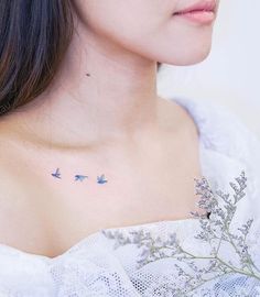 a woman's chest with three birds on it and flowers in the foreground