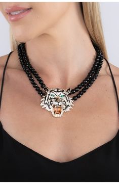 Sparkling crystals and glossy enamel finish the ferocious feline pendant hanging from a double strand onyx necklace. Spring ring clasp Onyx, cubic zirconia, enamel, goldtone plate Imported Black Crystal Pendant Necklace, Luxury Black Enamel Statement Necklace, Luxury Onyx Beaded Necklace, Black Multi-strand Necklace With Faceted Beads, Tiger Necklace Pendants, Black Multi-strand Costume Jewelry Necklace, Tiger Head, Onyx Necklace, Sparkling Crystal