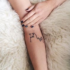 a woman's arm with a cat tattoo on her left wrist and the word cats written in black ink