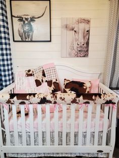 a baby crib in a room with pictures on the wall and cow print bedding