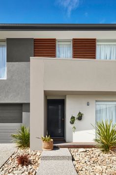 a modern house with gravel and plants in front