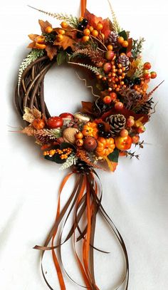 a wreath is hanging on the wall next to a candle and some leaves, berries, and acorns