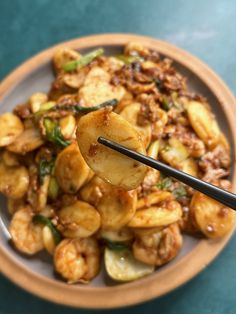 a plate full of food with chopsticks in it