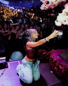 a woman kneeling down in front of a crowd with her hand up to the sky