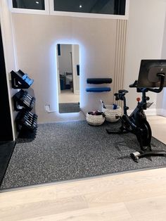 there is a bike and exercise equipment on the floor in front of a mirror with lights