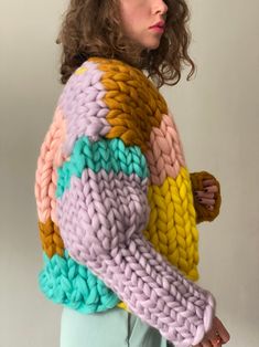 a woman with curly hair wearing a multicolored sweater