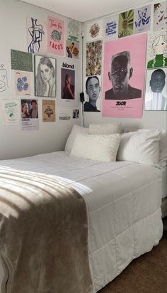 a white bed sitting in a bedroom next to a wall with pictures on it