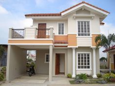 a white and orange two story house with a motorcycle parked in front of the door