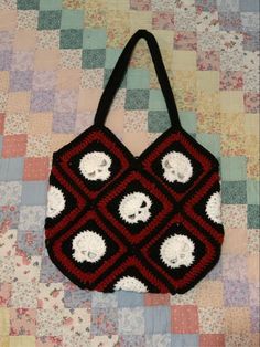 a crocheted bag with skulls on it sitting on top of a quilted surface