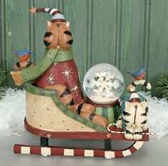 a wooden sleigh with two cats on it and a snow globe in the middle