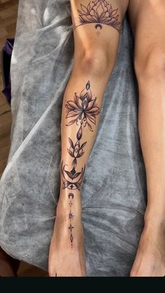 a woman's foot with tattoos on it and flowers in the middle of her leg