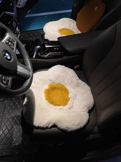 two fried eggs in the center of a car with black leather seats and steering wheel