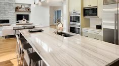 a kitchen with marble counter tops and an island in front of the stove top oven