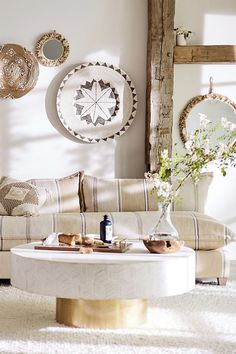 a living room with white furniture and mirrors on the wall, along with a coffee table