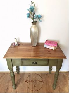 a wooden table with a vase on it and a book sitting on top of it