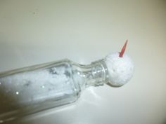 a glass bottle filled with white stuff and a red toothbrush sticking out of it