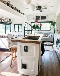 a kitchen and living room in a mobile home with wood flooring, white walls and cabinets