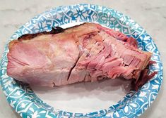 a piece of meat sitting on top of a blue and white plate