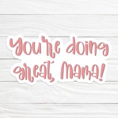 you're doing great mama sticker on a white wooden background with pink lettering