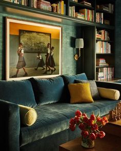 a living room with bookshelves, couches and paintings on the wall in it