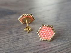 a pair of pink and gold earrings sitting on top of a wooden table next to each other