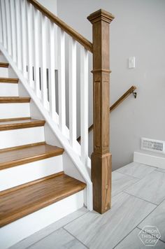 a white staircase with wooden handrails next to a heater on the floor