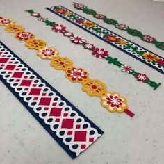 four different colored paper tapes on a table with white and red flowers in the middle