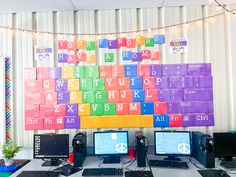 there are many computers on the desk with colorful blocks attached to the wall behind them