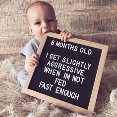 a baby holding a sign that says, 8 months old i get slightly aggressive when i'm not fed enough