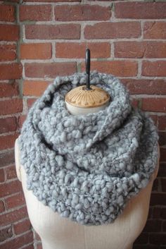 a mannequin head wearing a gray knitted scarf