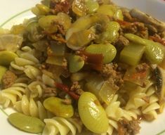 a plate with pasta, meat and vegetables in it on a green stripe around the edge