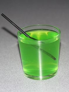 a glass filled with green liquid and a black stick sticking out of it's side