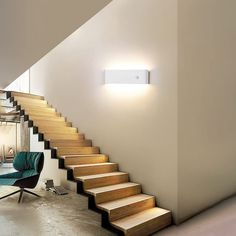 there is a light that is on the wall above the stairs in this room,