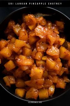 a bowl filled with pineapple chutney sitting on top of a black table